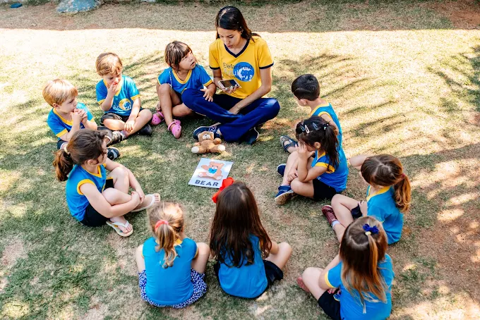 Crianças em roda de leitura com a educadora no quintal